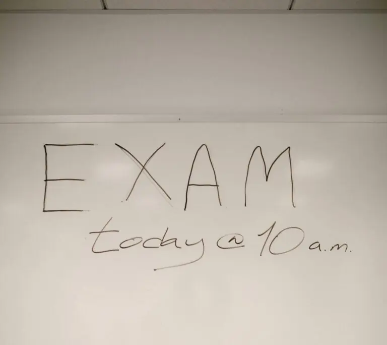 A whiteboard message announcing an exam scheduled for today at 10 a.m. in a classroom setting.
